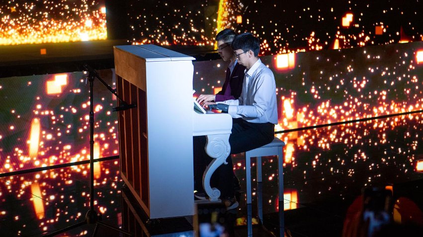 智能仿生手使用者古月與少年鋼琴家舒海峰合奏。主辦方供圖